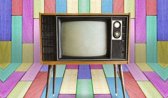 Old vintage TV television on colorful wooden wall background.