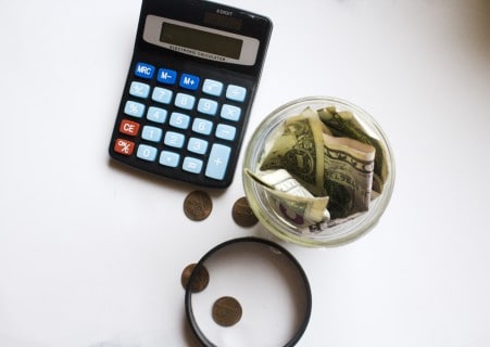 retirement savings in a jar and a calculator to figure investment