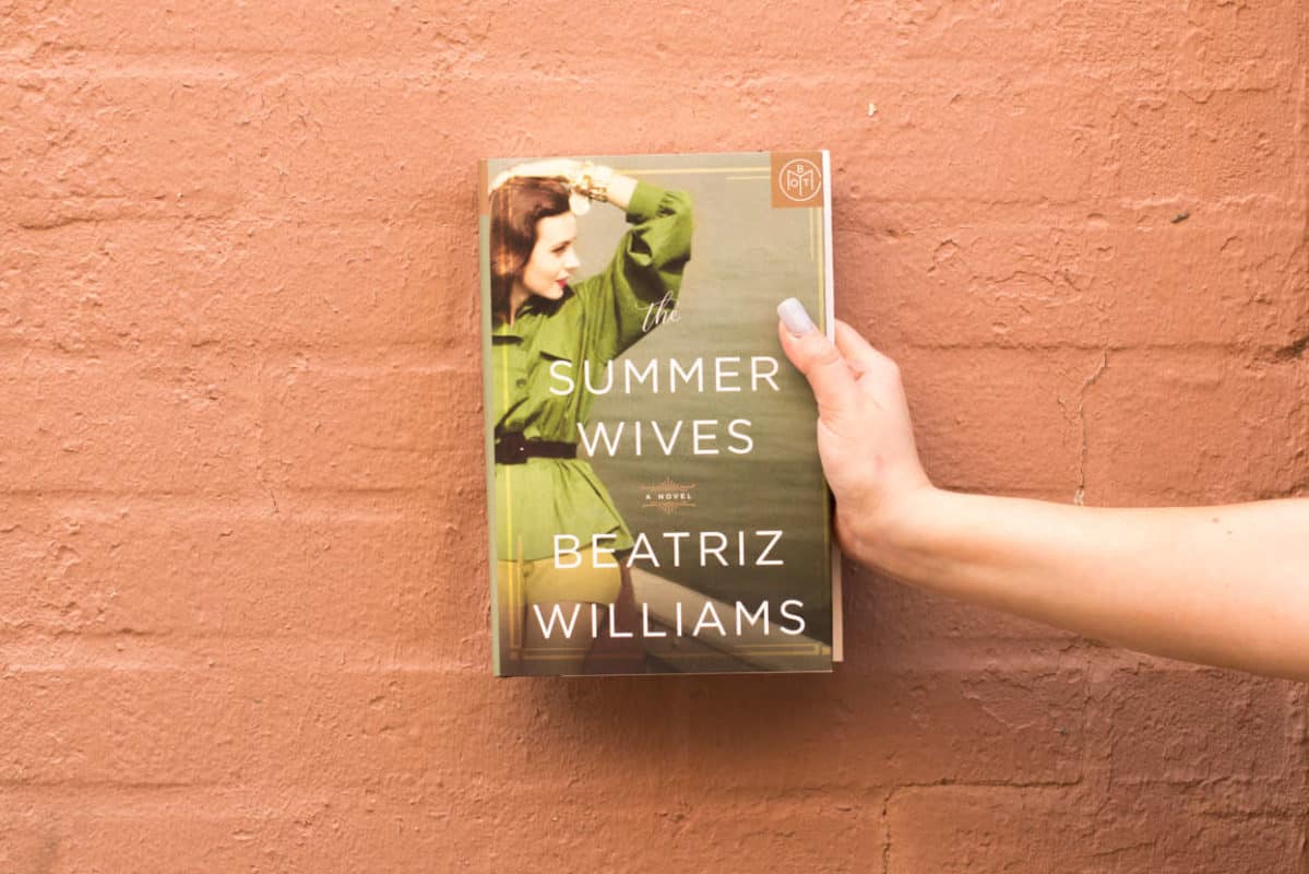 The Summer Wives held in front of an orange painted brick wall