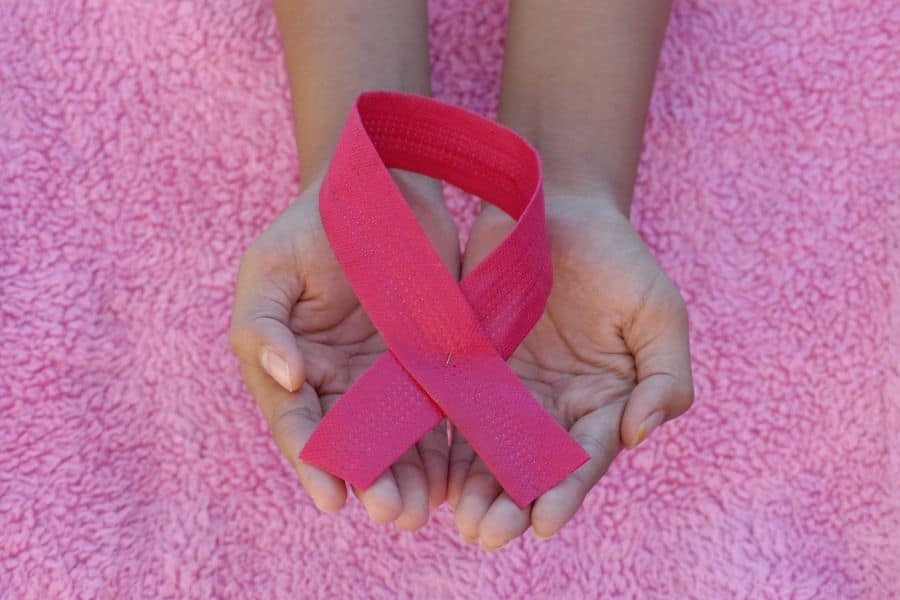Person holding a breast cancer awareness ribbon