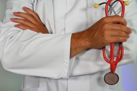 A doctor holding a red stethoscope to check health issues