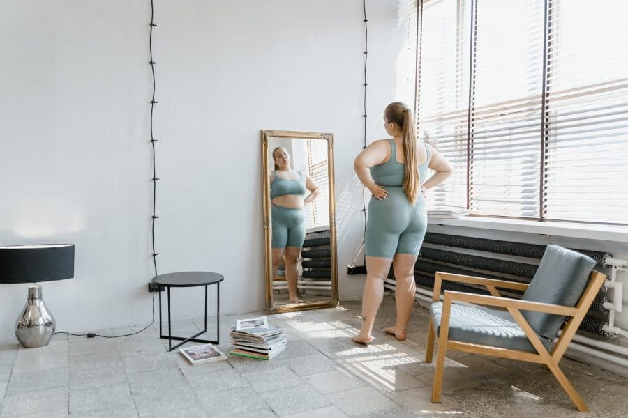 Woman in workout clothes looking at herself in the mirror