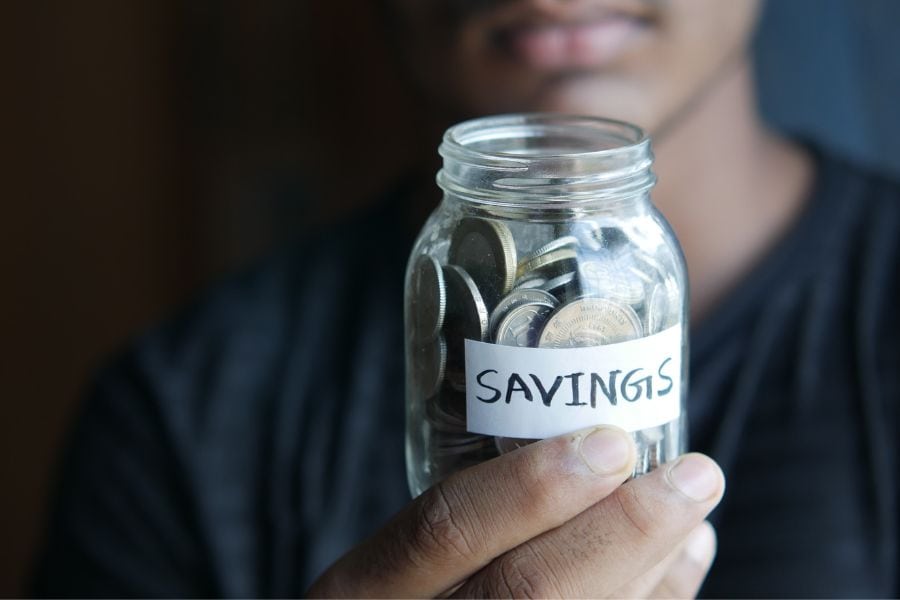 Person holding a jar of savings set aside for their personal loans