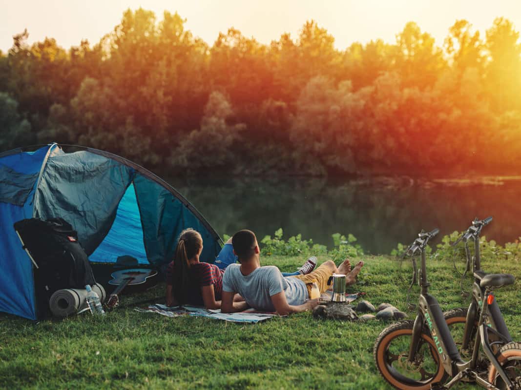 Couple laying outside a tent while camping and ebiking