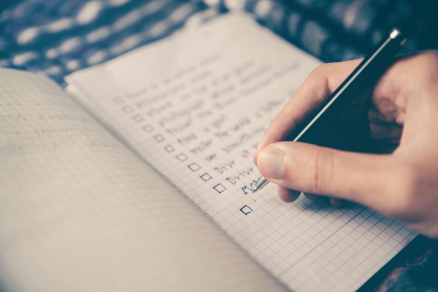 Person writing a to-do list to stay productive